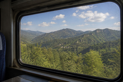 Blick aus dem Zugfenster auf eine grüne Berglandschaft, China